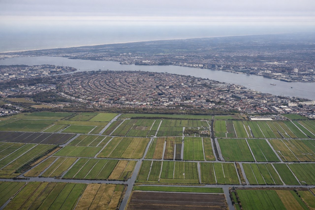 Aerial window seat view during landing at Amsterdam (left side) — Amsterdam canal ring (UNESCO World Heritage grachtengordel), IJ waterfront and Amsterdam Centraal station, Westergasfabriek and Jordaan district, Haarlemmermeer polder fields