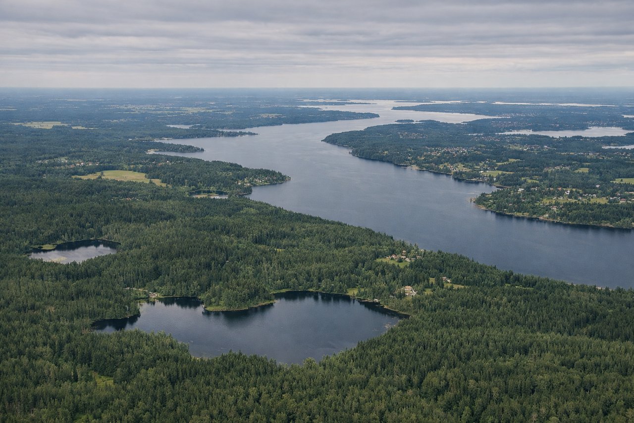 Right window seat view during landing at Stockholm (ARN) — Lake Mälaren (northern bays), Sigtuna old town, Steninge Slott (lakeside manor), forested/agricultural terrain north of Stockholm