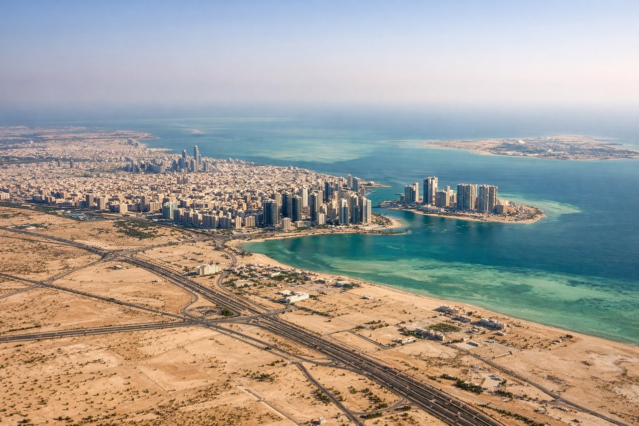 Right window seat view during landing at Abu Dhabi (AUH) — Yas Island (Ferrari World, Yas Marina Circuit), Abu Dhabi city skyline in the distance, Persian Gulf coastline, Saadiyat Island