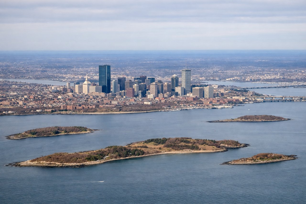 Left window seat view during takeoff from Boston (BOS) — Downtown Boston skyline, Charles River, Back Bay, Boston Harbor islands