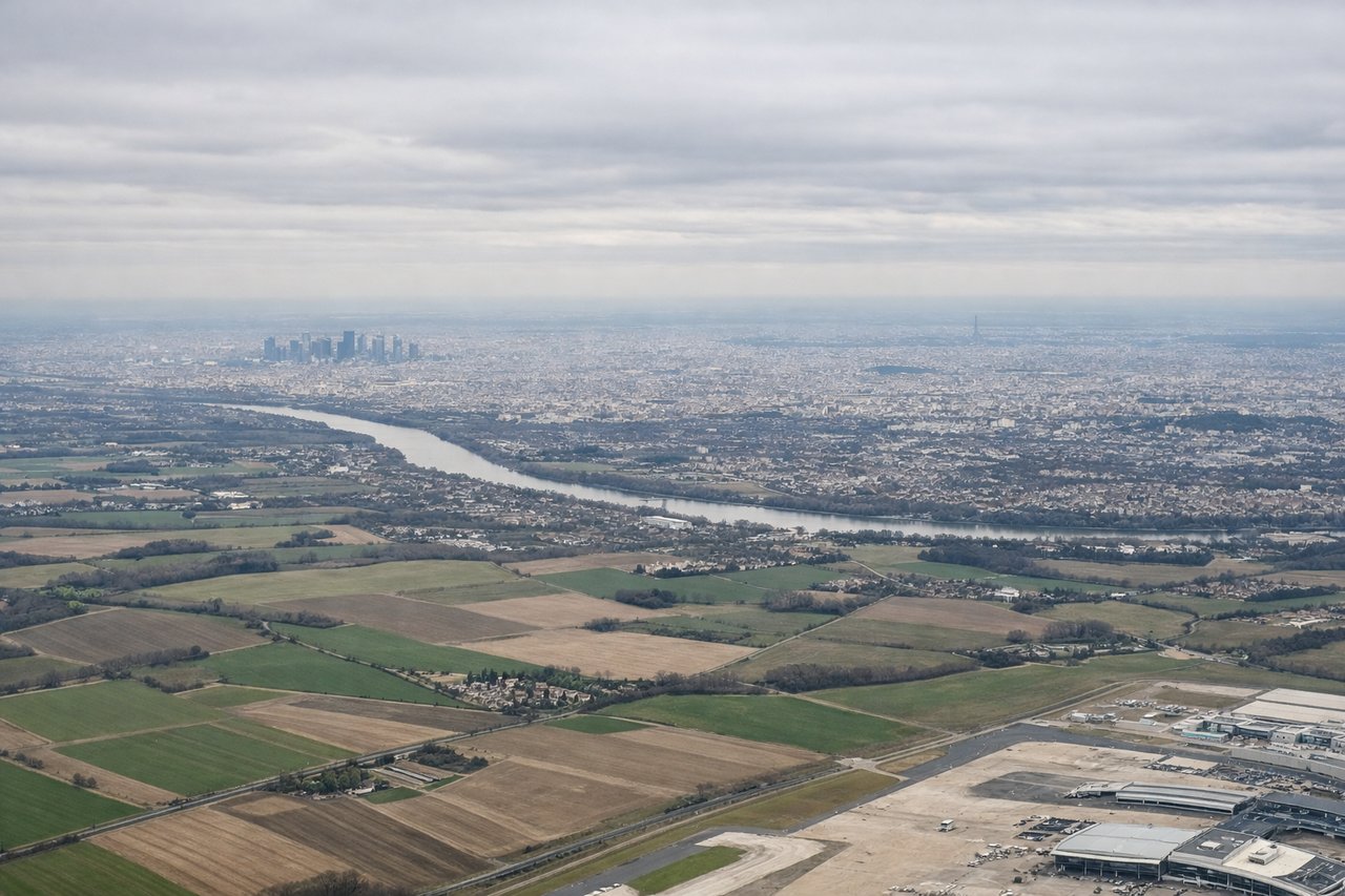 Aerial window seat view during takeoff from Paris (left side) — Eiffel Tower, La Défense skyscraper district, Seine River, Paris rooftops