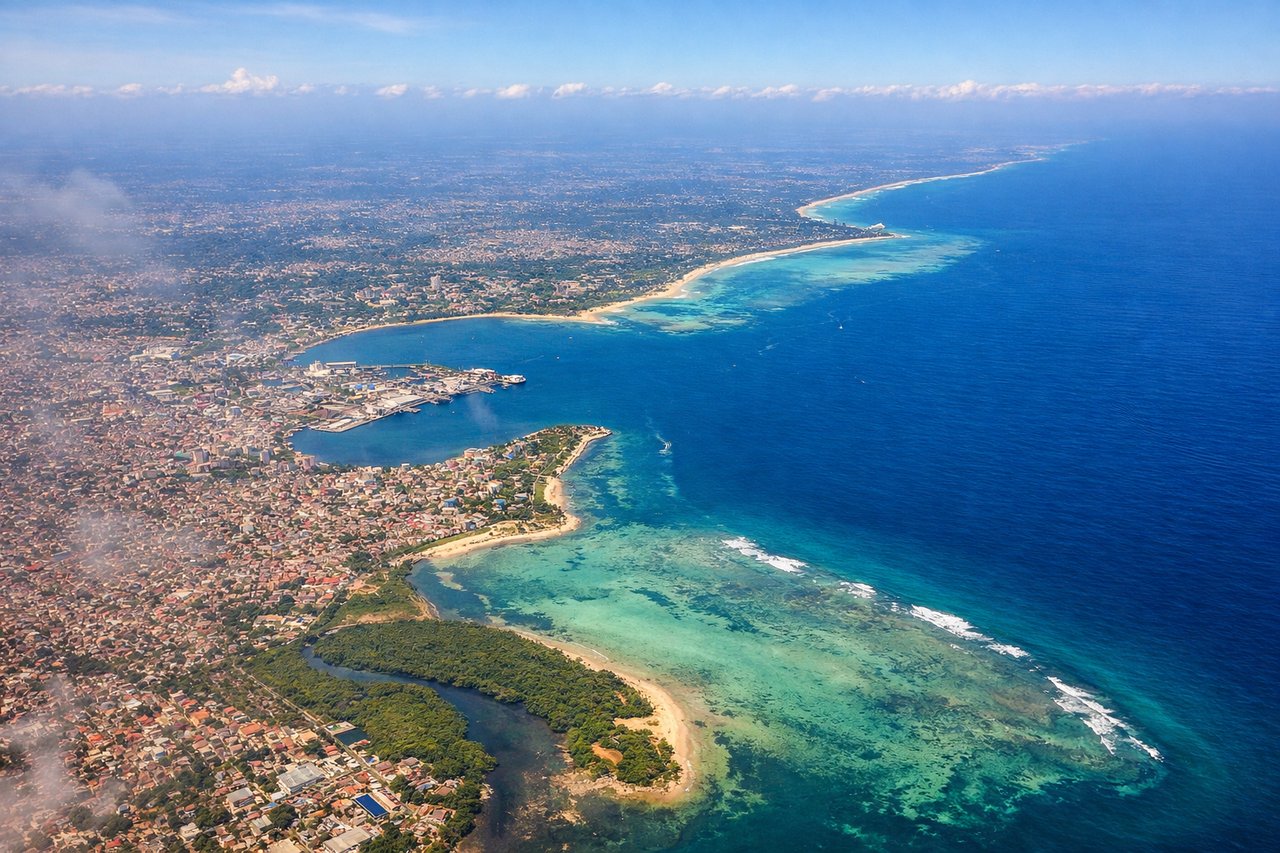 Right window seat view during takeoff from Dar Es Salaam (DAR) — Dar es Salaam harbor and port, Msasani Bay peninsula, Indian Ocean coastline, Kigamboni ferry crossing area