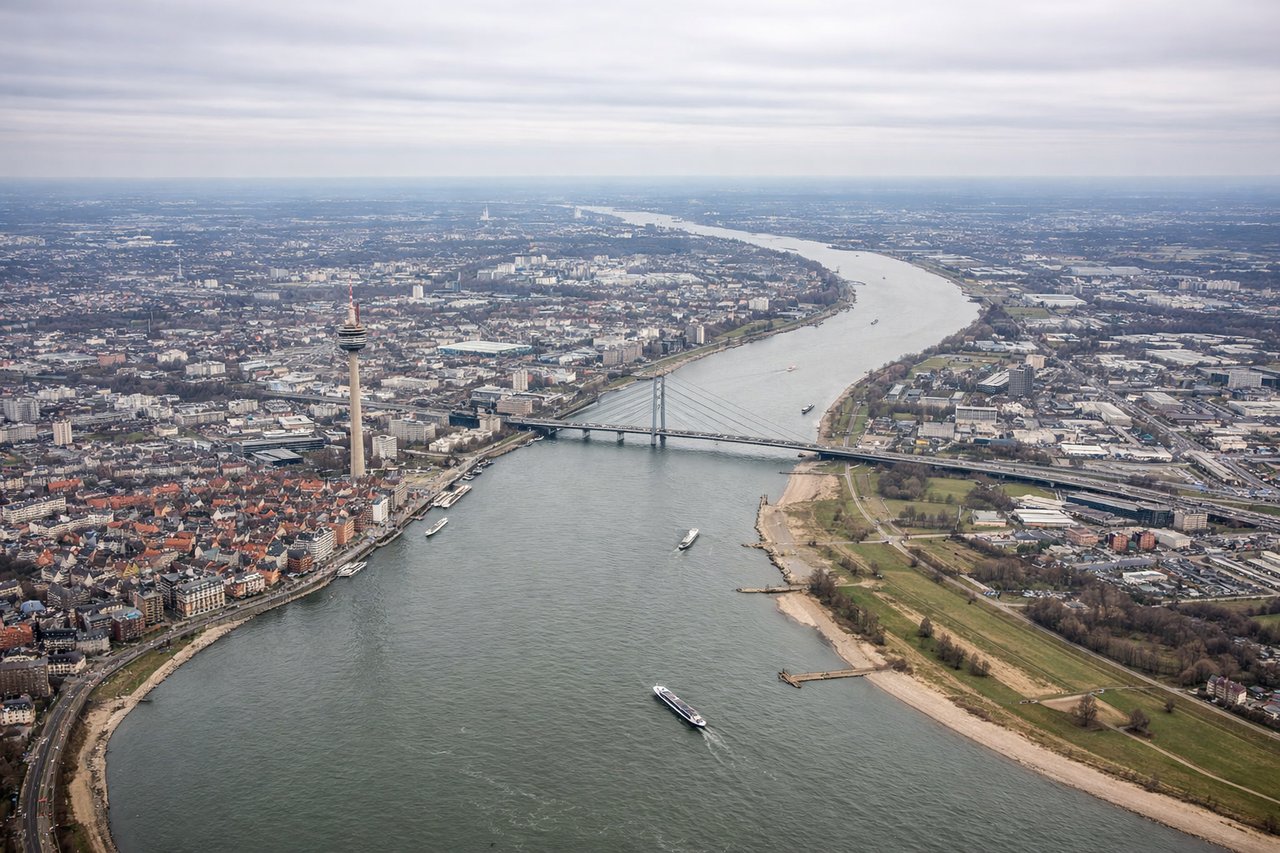 Left window seat view during takeoff from Duesseldorf (DUS) — Rhine River, Düsseldorf city skyline, Rheinturm (Rhine Tower), Rhine river bends near the Altstadt