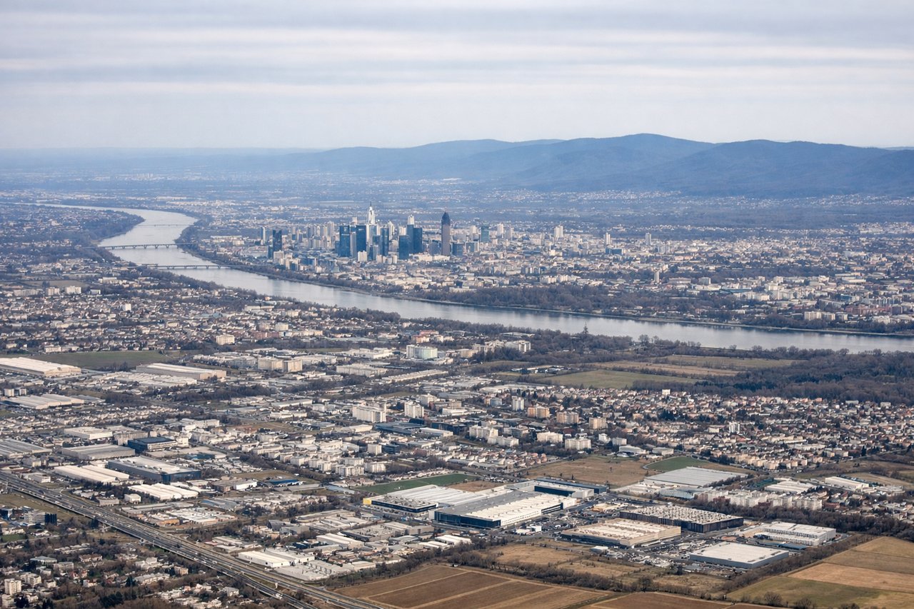Aerial window seat view during takeoff from Frankfurt (left side) — Frankfurt Bankenviertel skyline, Main River bend through the city, Taunus hills to the northwest, Rhine-Main floodplain