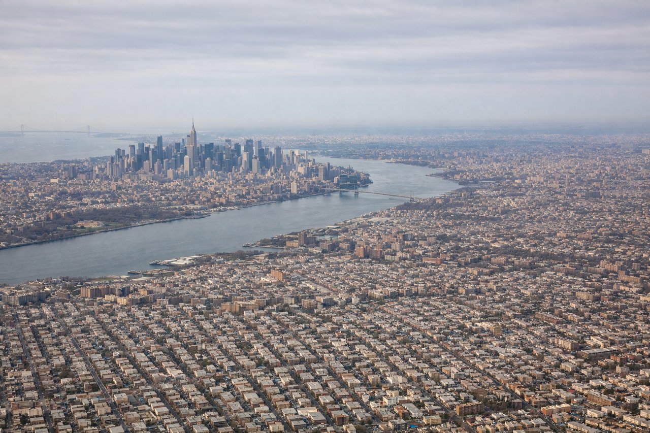 Aerial window seat view during takeoff from New York (left side) — Manhattan skyline, Verrazano-Narrows Bridge, Jamaica Bay, East River bridges (Brooklyn and Manhattan Bridges)