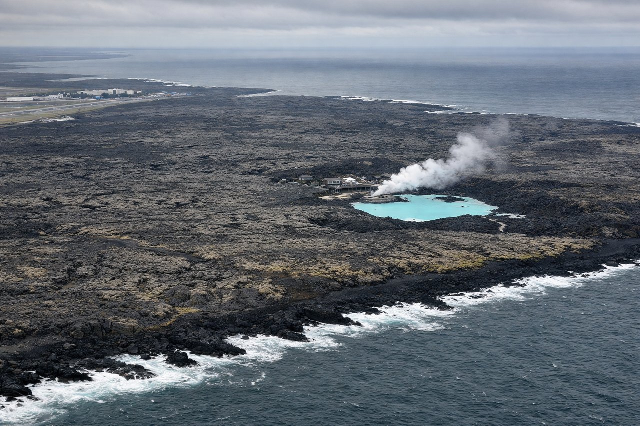 Aerial window seat view during landing at Keflavik (right side) — Reykjanes lava fields, Blue Lagoon geothermal pools (pale turquoise against black lava), Atlantic coastline of Reykjanes Peninsula, Faxaflói Bay in the distance