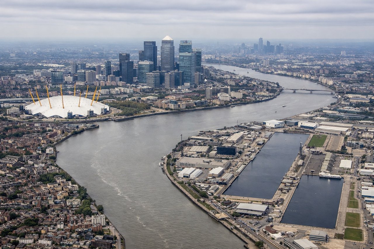 Aerial window seat view during landing at London (left side) — River Thames and its meanders, Isle of Dogs, Canary Wharf financial district, Thames Estuary marshlands