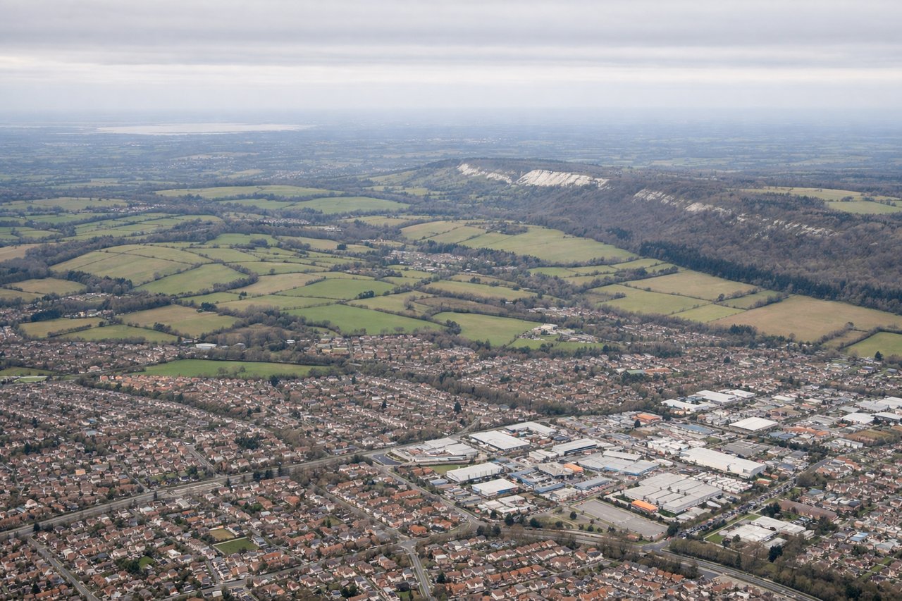 Aerial window seat view during takeoff from London (left side) — Thames estuary, London sprawl (visible as urban grid), Kent coastline, English Channel