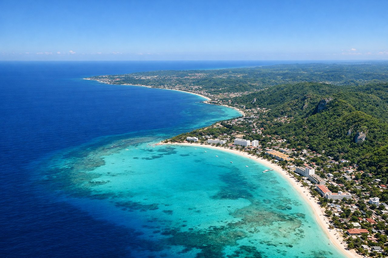 Aerial window seat view during takeoff from Montego Bay (left side) — Montego Bay harbor and cruise ship anchorage, Caribbean Sea (turquoise shallow waters), northern Jamaica coastline with white sand beaches, Doctor's Cave Beach area