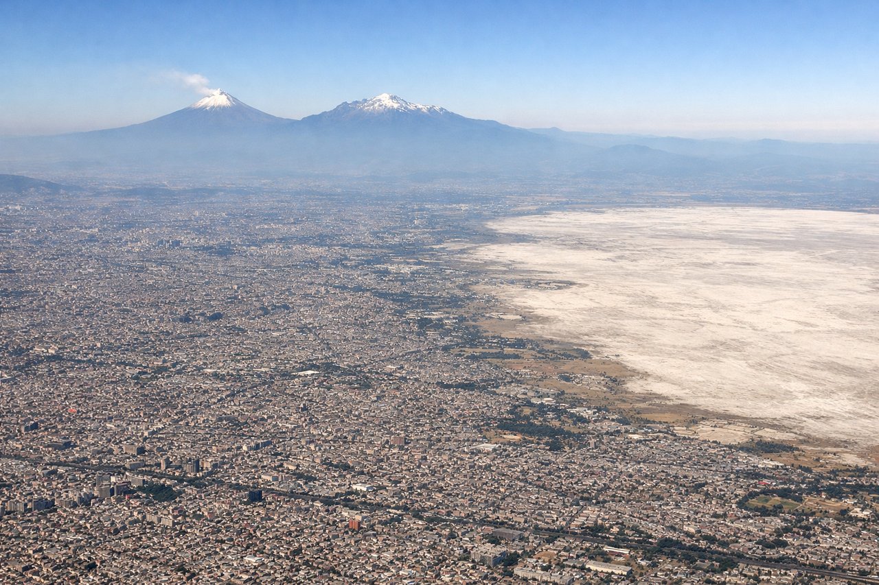 Aerial window seat view during landing at Mexico City (left side) — Popocatépetl volcano, Iztaccíhuatl volcano, Sierra Nevada range, Valley of Mexico basin
