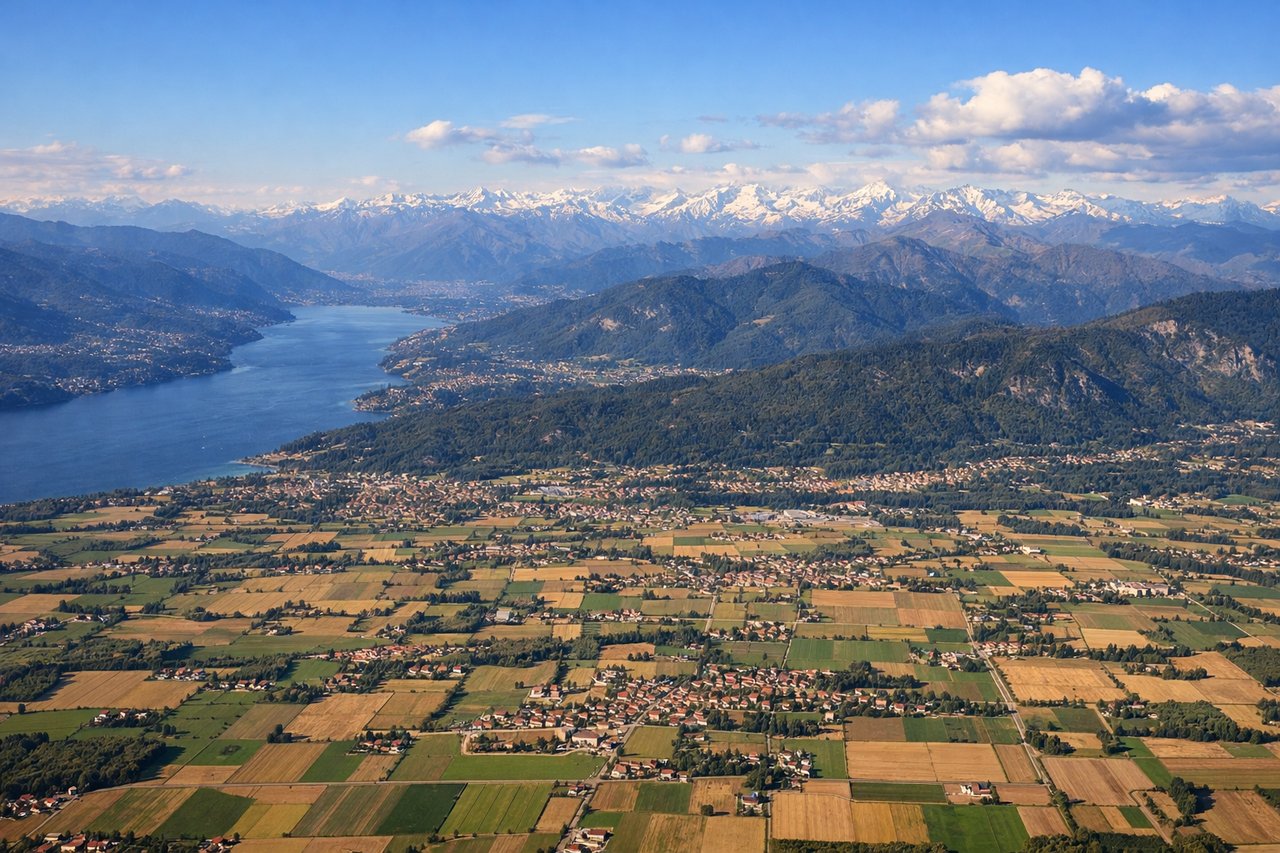 Aerial window seat view during landing at Milano (left side) — Southern Alps and Pre-Alps (Monte Rosa and Gotthard massif region on distant horizon), Lake Como's distinctive Y-shape, Lombardy Plain with Milan's metropolitan area, Ticino River valley