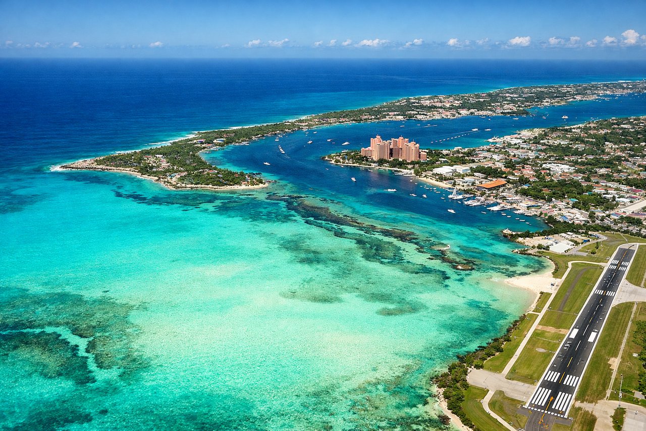 Right window seat view during landing at Nassau (NAS) — New Providence Island northern shore, Paradise Island (northeast of Nassau), turquoise shallow water banks, Nassau Harbor