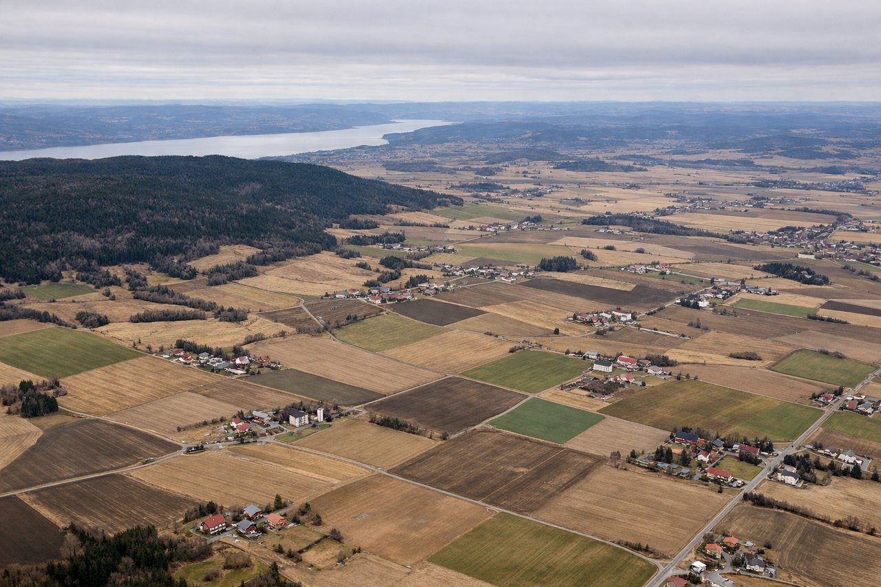 Left window seat view during takeoff from Oslo (OSL) — Lake Hurdalssjøen, Gardermoen's surrounding farmland patchwork, forested ridges of eastern Akershus, distant hills toward the Swedish border