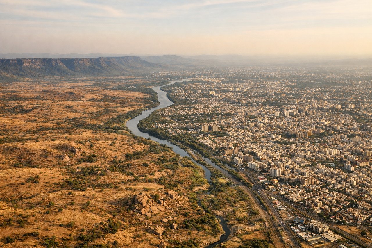 Left window seat view during landing at Pune (PNQ) — Mula River (visible as a linear feature through the valley), Pune city grid and built-up areas to the north, Deccan Plateau escarpment features in the distance, Katraj Ghat hills visible on the horizon to the northwest