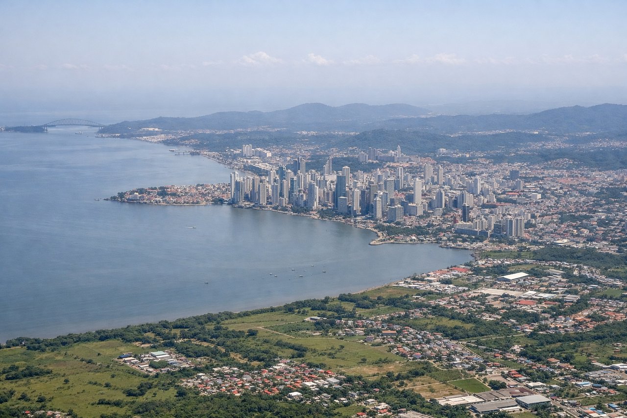 Left window seat view during takeoff from Panama City (PTY) — Panama City urban grid, Gatun Lake (visible as a large water body 15–20 miles northeast), Panama Canal's Gatun Locks area, Colón province lowlands