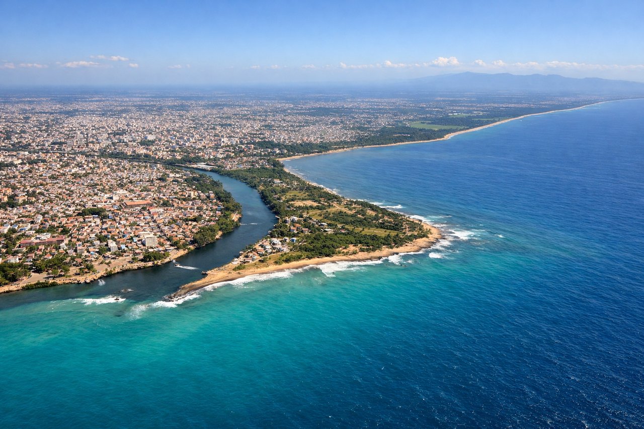 Left window seat view during landing at Santo Domingo (SDQ) — Caribbean coastline, Santo Domingo urban sprawl, Ozama River delta, distant Cordillera Central mountains on the horizon