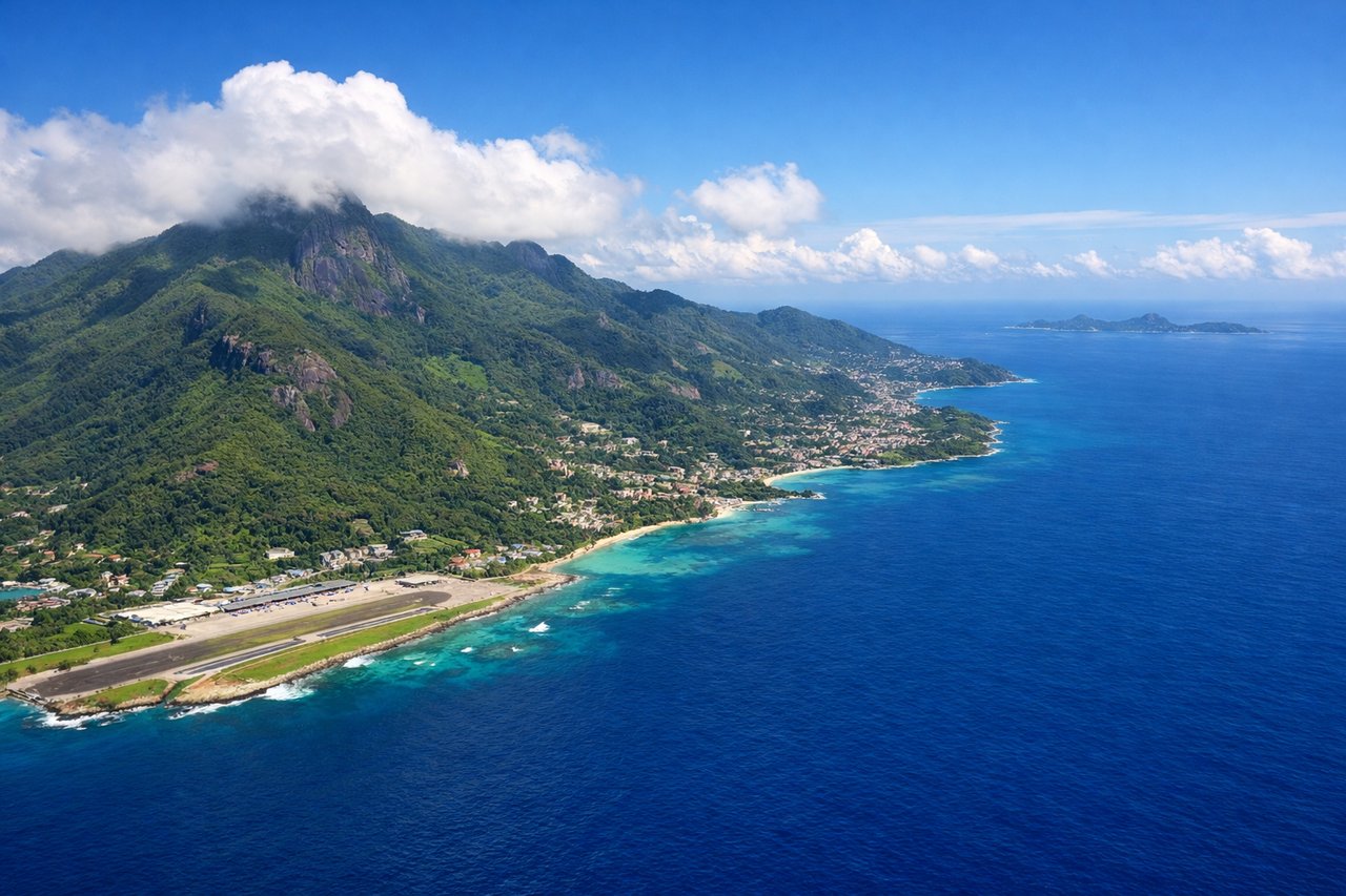 Aerial window seat view during landing at Mahe (left side) — Morne Seychellois peak (905m, Mahe's highest point), Victoria harbour and town, Sainte Anne Marine National Park islands, coral reef lagoons surrounding Mahe
