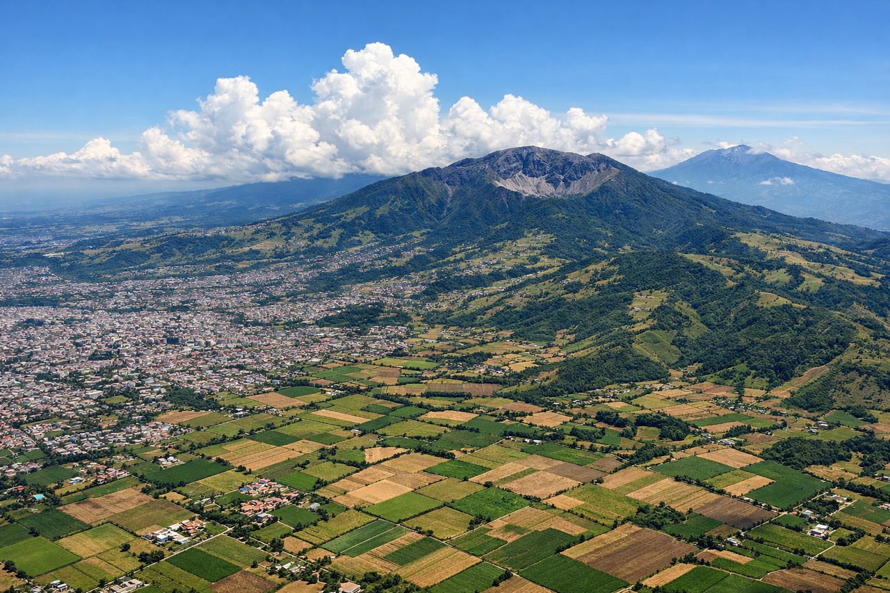 Aerial window seat view during takeoff from San Jose (right side) — Irazú Volcano (3,432m), Turrialba Volcano, the Central Valley urban sprawl of San José, Caribbean lowlands visible to the northeast