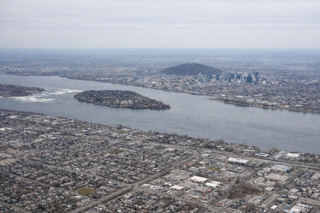 Aerial window seat view during takeoff from Montreal (right side) — St. Lawrence River (flowing southeast below), Laurentian Mountains (northern horizon), Montreal urban sprawl (receding southwest), Île Perrot (visible in river to the west)