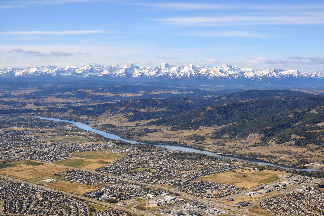 Right window seat view during takeoff from Calgary (YYC) — Rocky Mountain front ranges (including peaks near Canmore/Kananaskis), Bow River valley, Calgary foothills, city skyline falling behind on the right