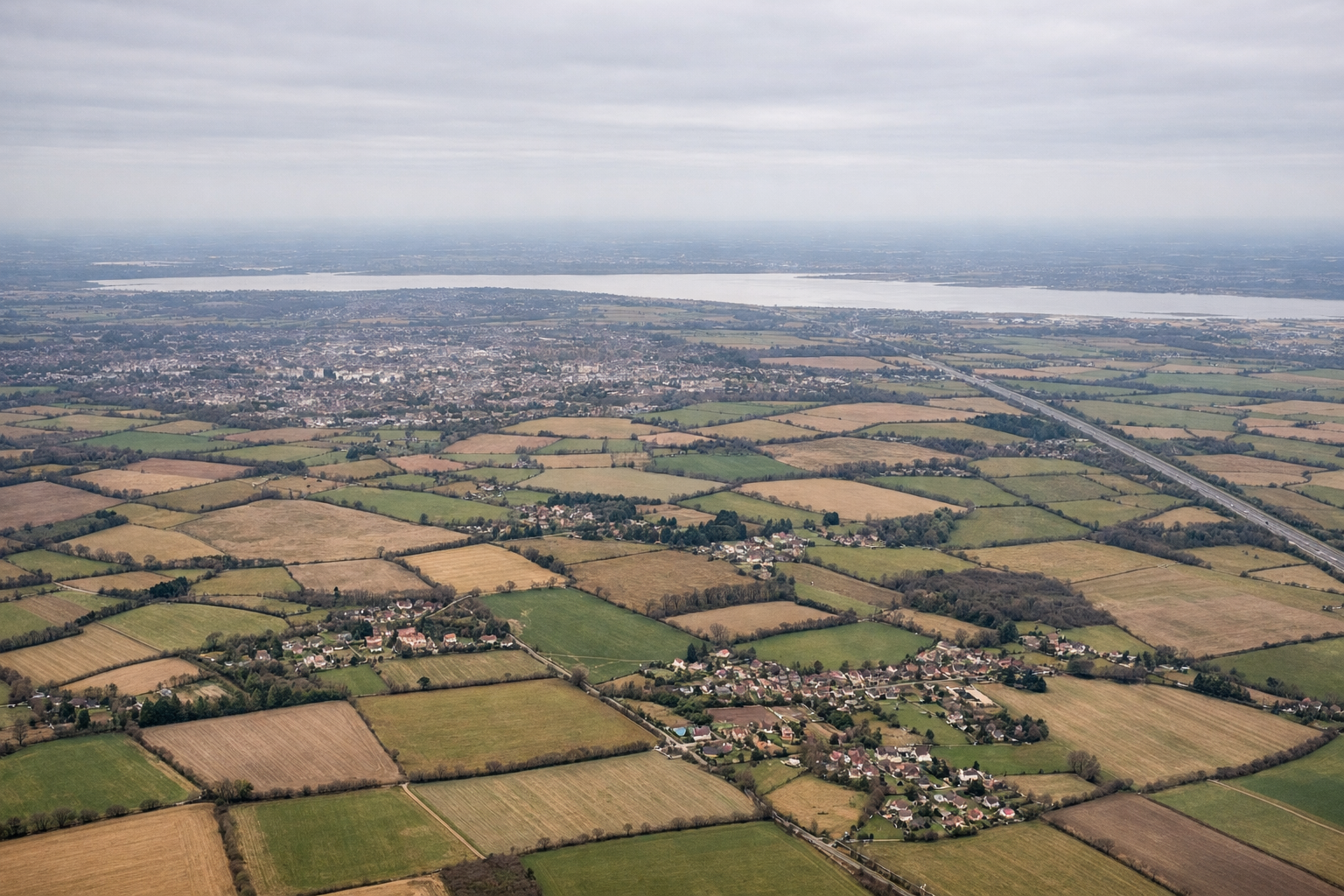 Aerial window seat view during landing at London (right side) — Distant London skyline, Essex farmland patchwork, River Stort valley
